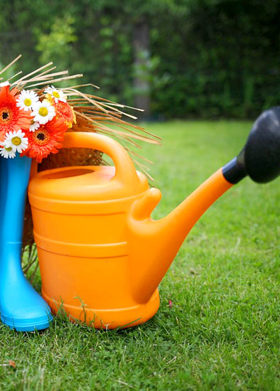 Gardening tools and watering can on a green lawn
